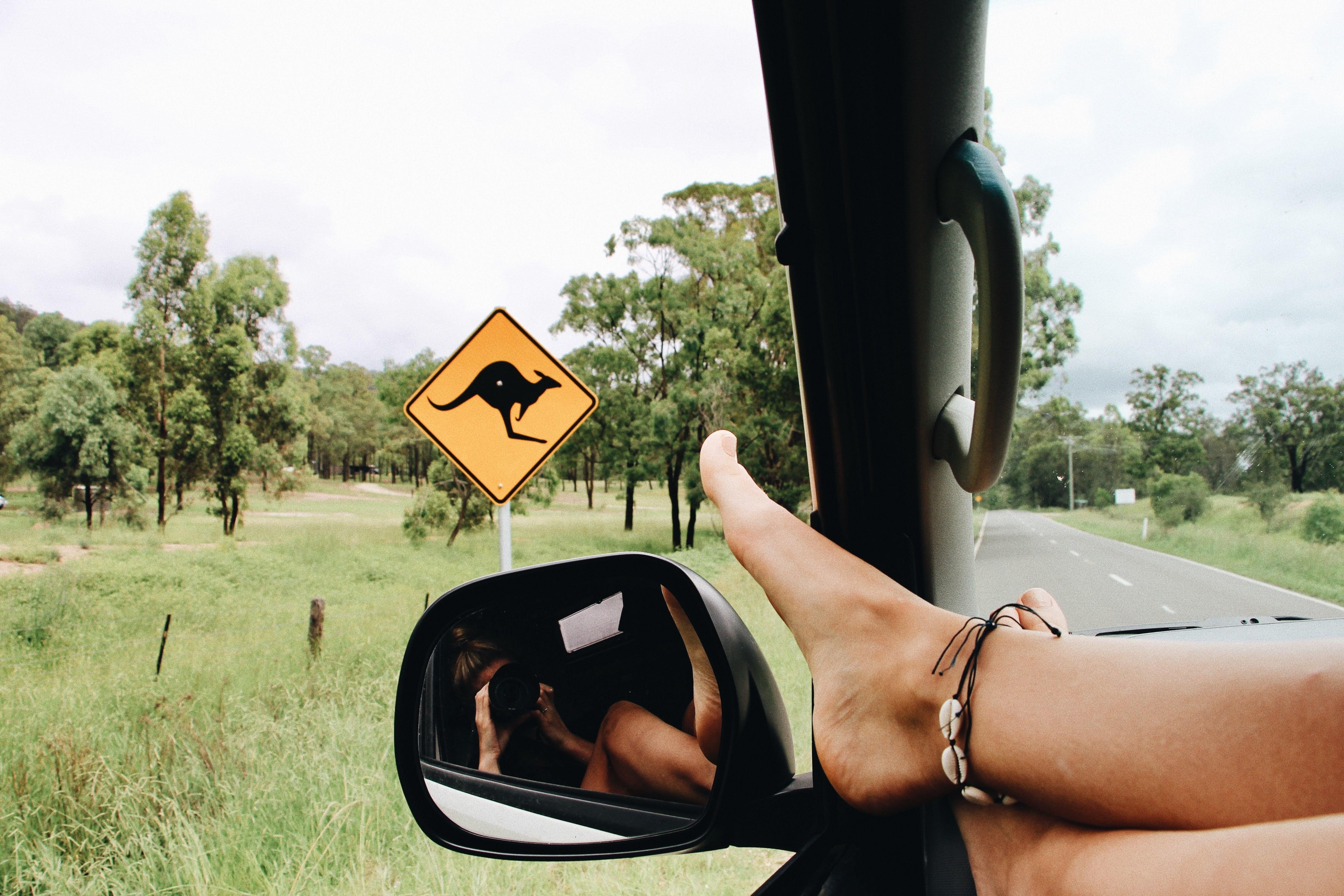 Füße am Auto-Rückspiegel vor Känguruh-Schild