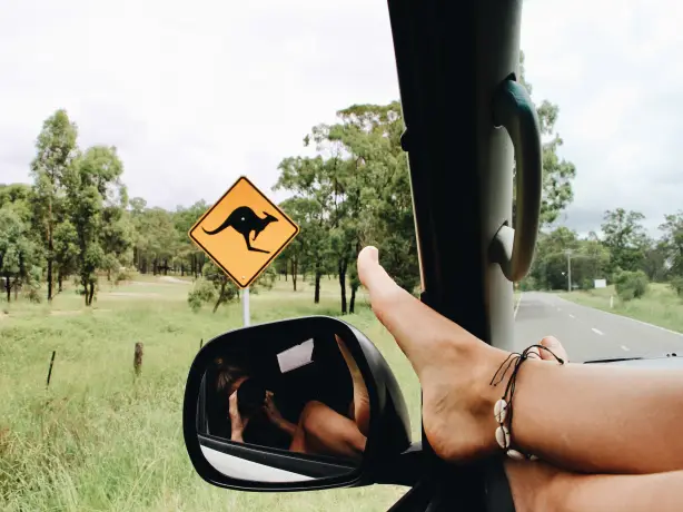 Füße am Auto-Rückspiegel vor Känguruh-Schild