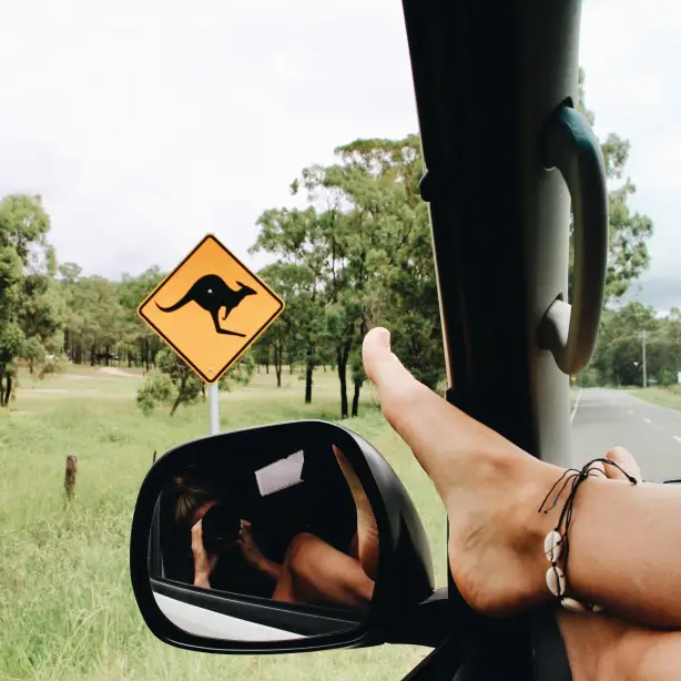 Füße am Auto-Rückspiegel vor Känguruh-Schild
