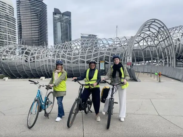 Drei Frauen posieren mit ihren Fahrrädern in Melbourne