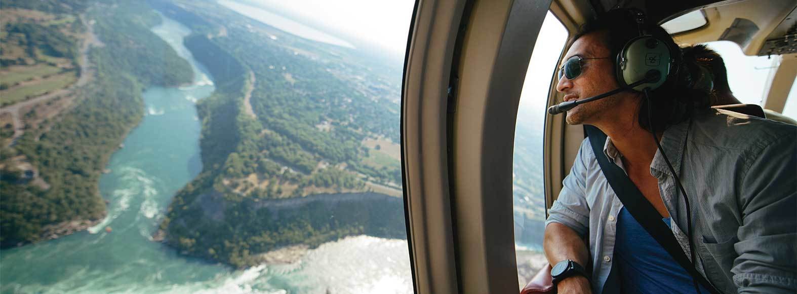 A man looking out the window of a helicopter above the Niagara Falls in Canada.