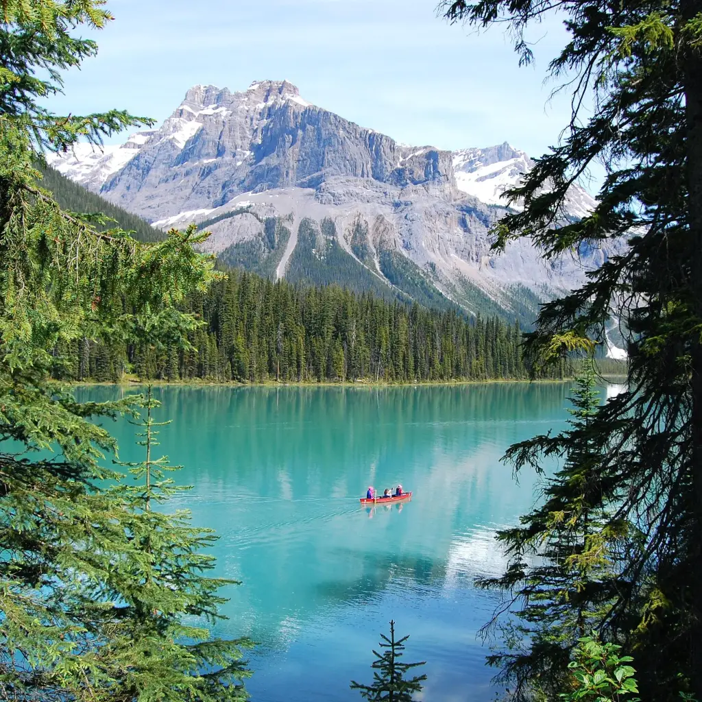 Een kano peddelt over Emerald Lake in Yoho National Park, British Columbia, omringd door bomen en bergen.