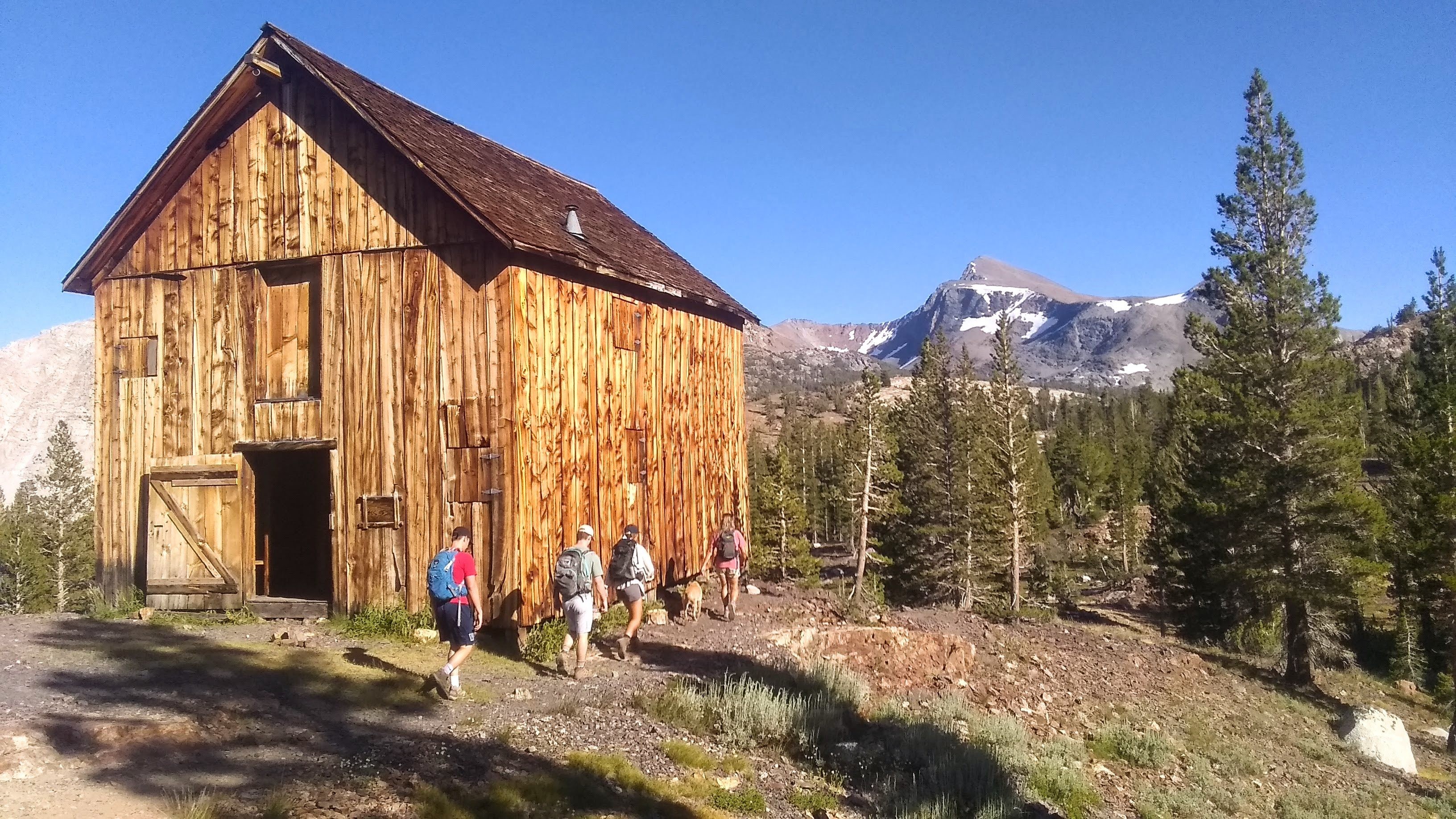 Eine Familie wandert an einer Holzhütte im Yosemite-Nationalpark, Kalifornien, USA, vorbei