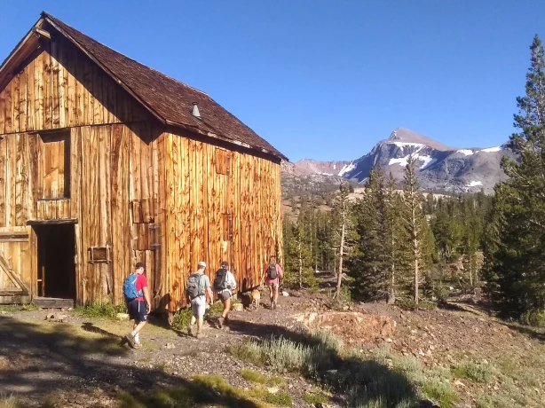 Eine Familie wandert an einer Holzhütte im Yosemite-Nationalpark, Kalifornien, USA, vorbei