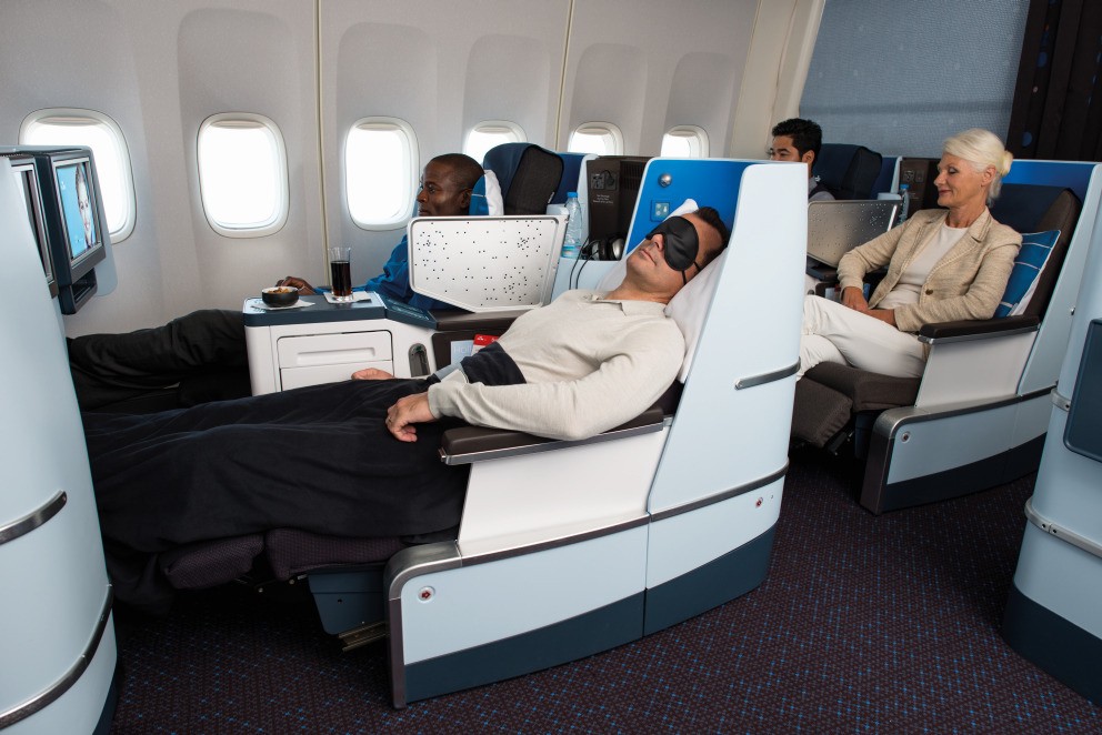 Passengers relaxing in lie-flat business class seats on an international flight.