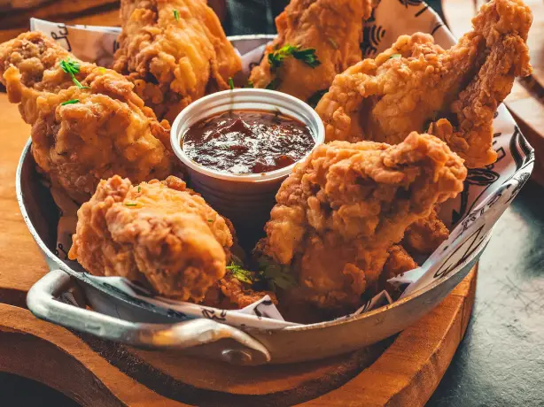 Knusprig frittiertes Hähnchen, das typische Kentucky Fried Chicken, serviert mit einem Dip