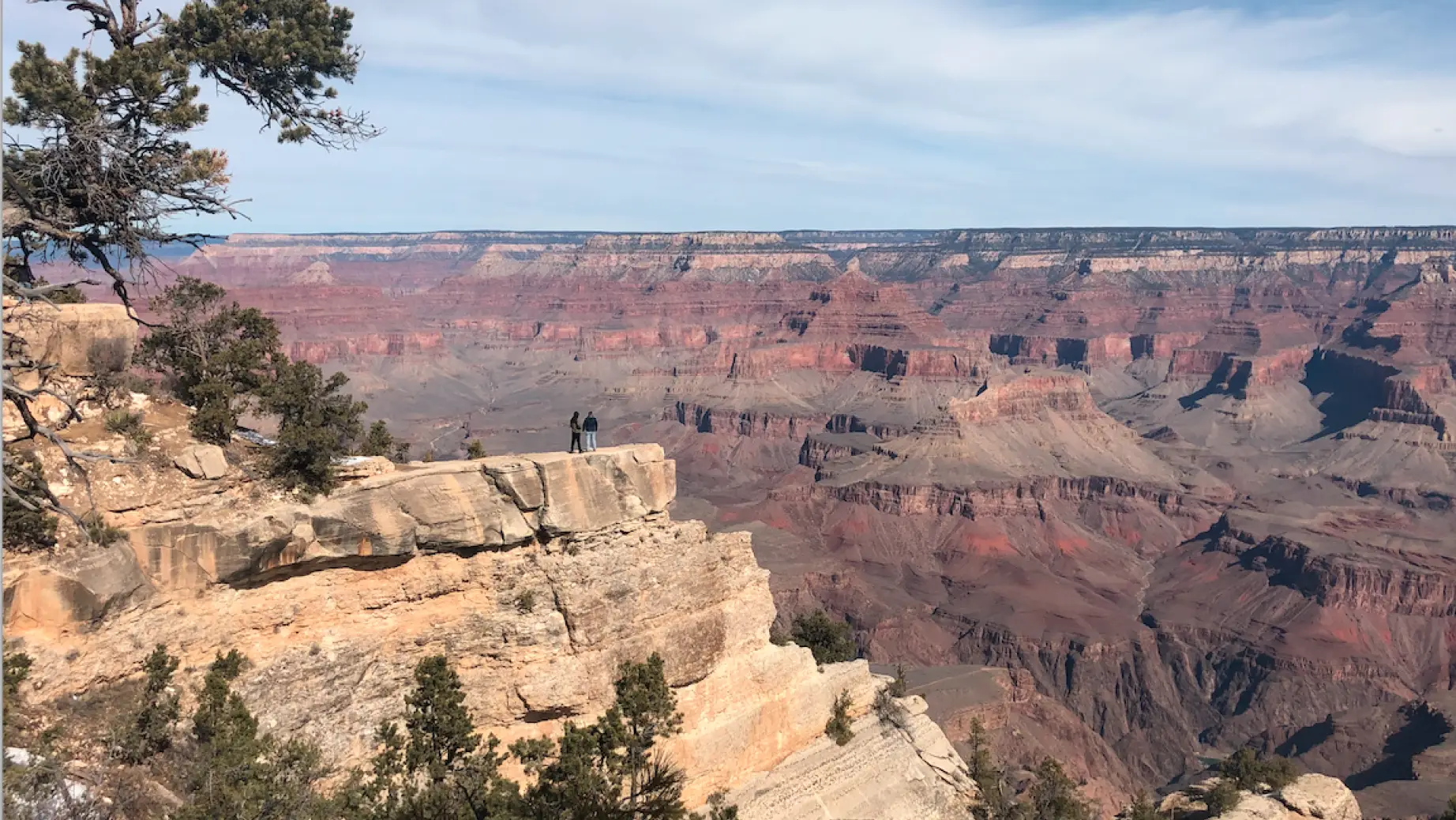 Zwei Menschen stehen am Rand eines Kraters und blicken über den Grand Canyon in Arizona.