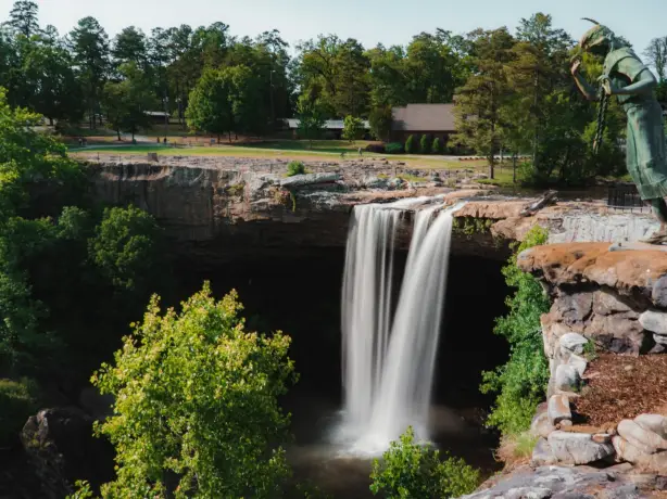 Noccalula Falls in Alabama mit Wasserfall, Felsklippe und einer Bronzestatue in