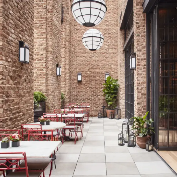 Een restaurantje in een historisch hotel in New York, rode stoelen en witte tafels tussen stenen muren