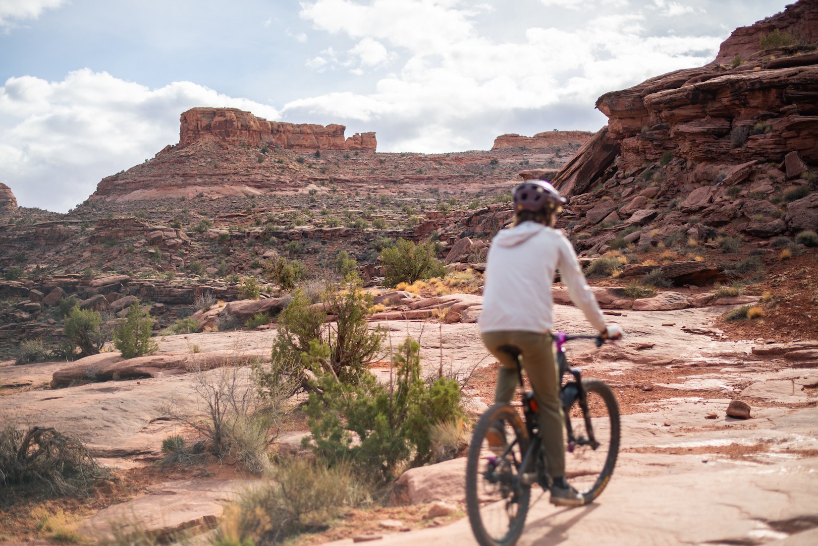 Eine Frau radelt durch Grand County in Utah, USA, umgeben von roten Felsformationen.