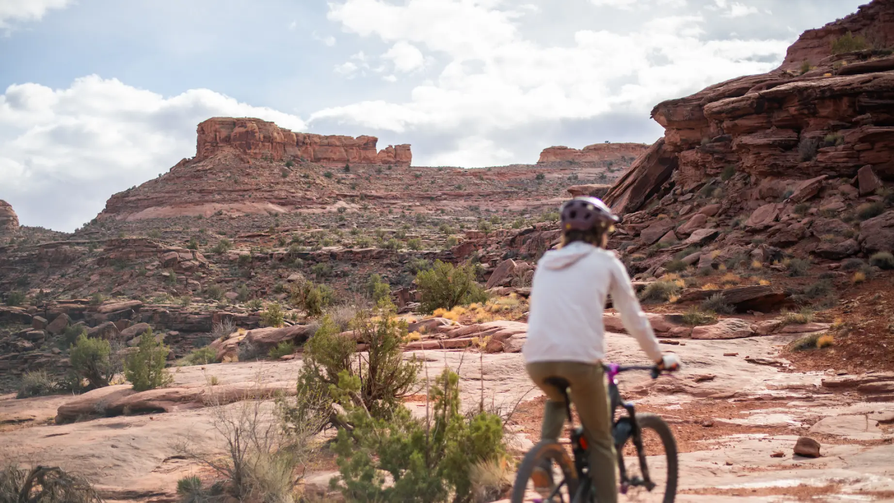 Eine Frau radelt durch Grand County in Utah, USA, umgeben von roten Felsformationen.