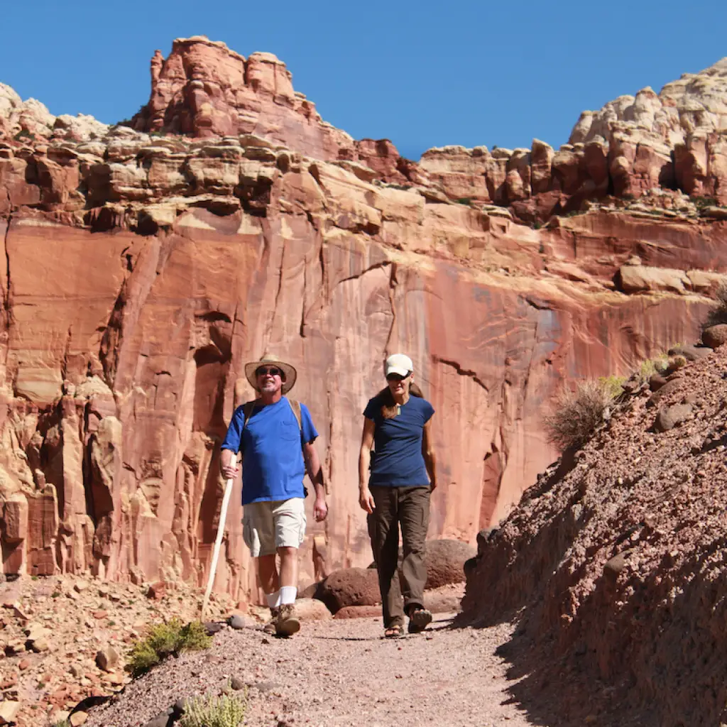 Zwei Menschen wandern durch die rote Felslandschaft im Capitol Reef Nationalpark in Utah, USA