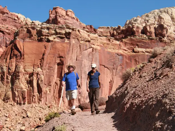 Zwei Menschen wandern durch die rote Felslandschaft im Capitol Reef Nationalpark in Utah, USA
