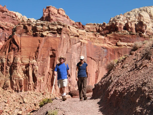 Zwei Menschen wandern durch die rote Felslandschaft im Capitol Reef Nationalpark in Utah, USA