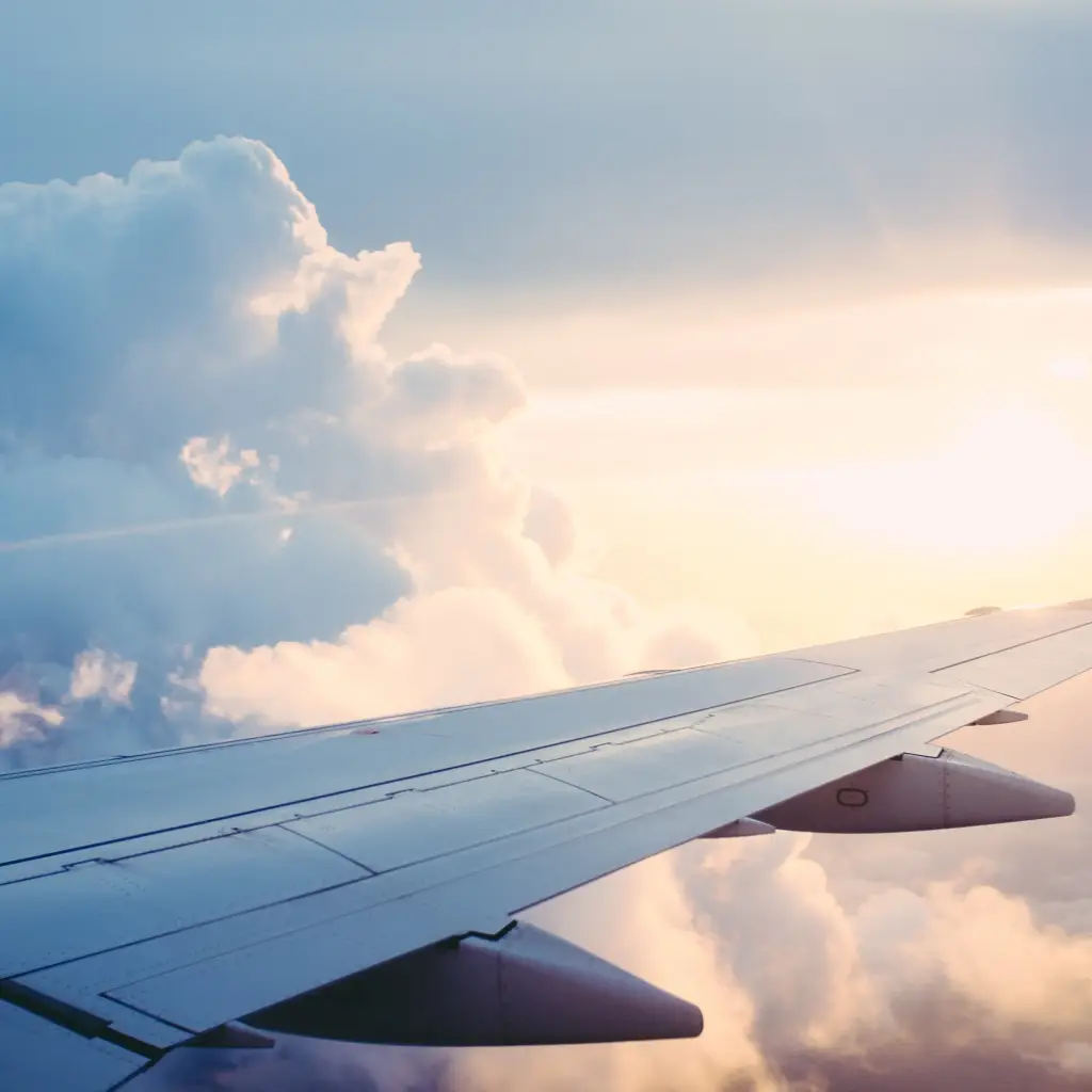 Blick auf Flugzeugflügel in den Wolken mit Sonne