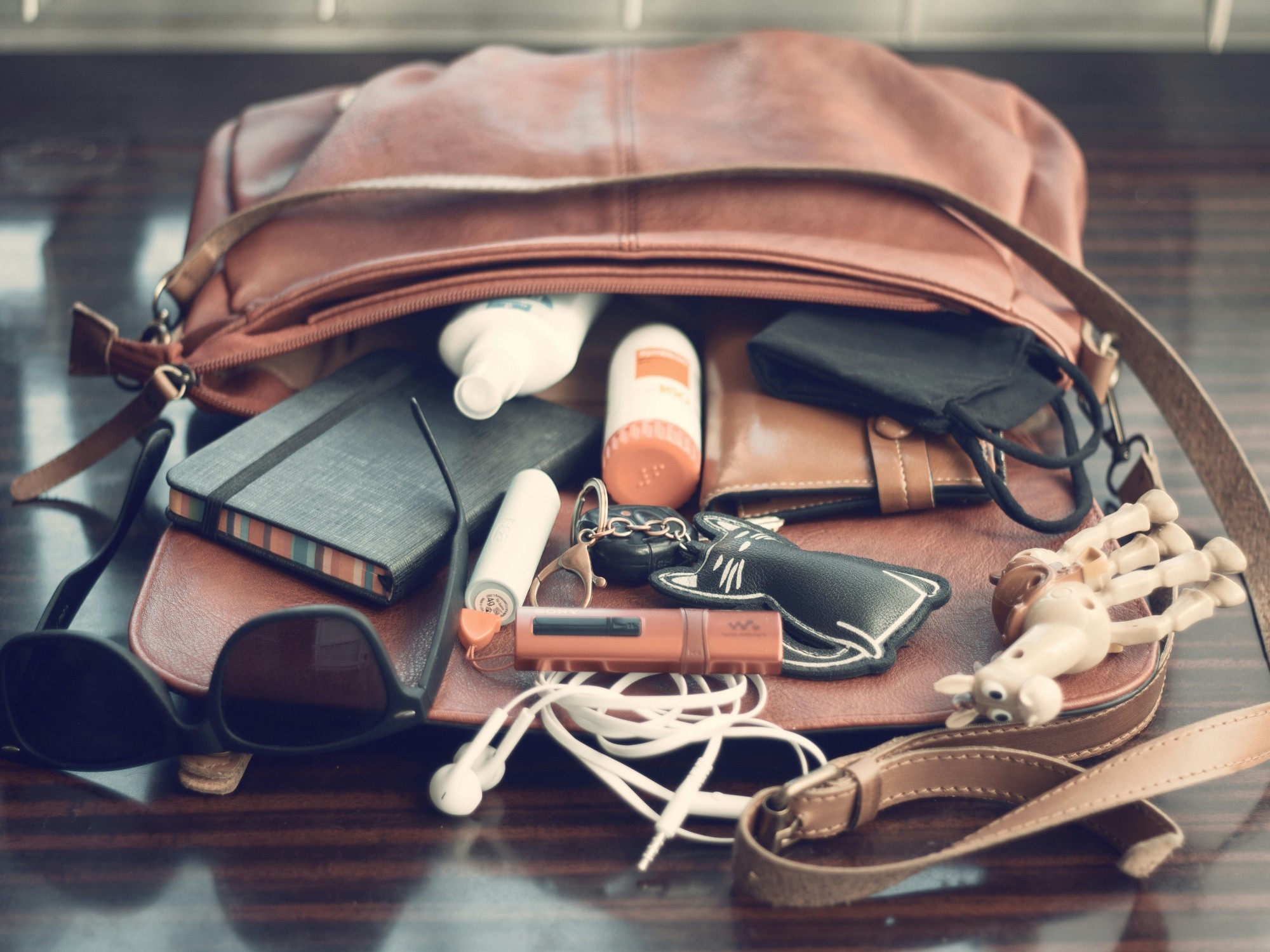 Liegende und geöffnete Handtasche mit herausfallenden Gegenständen