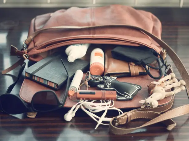 Liegende und geöffnete Handtasche mit herausfallenden Gegenständen