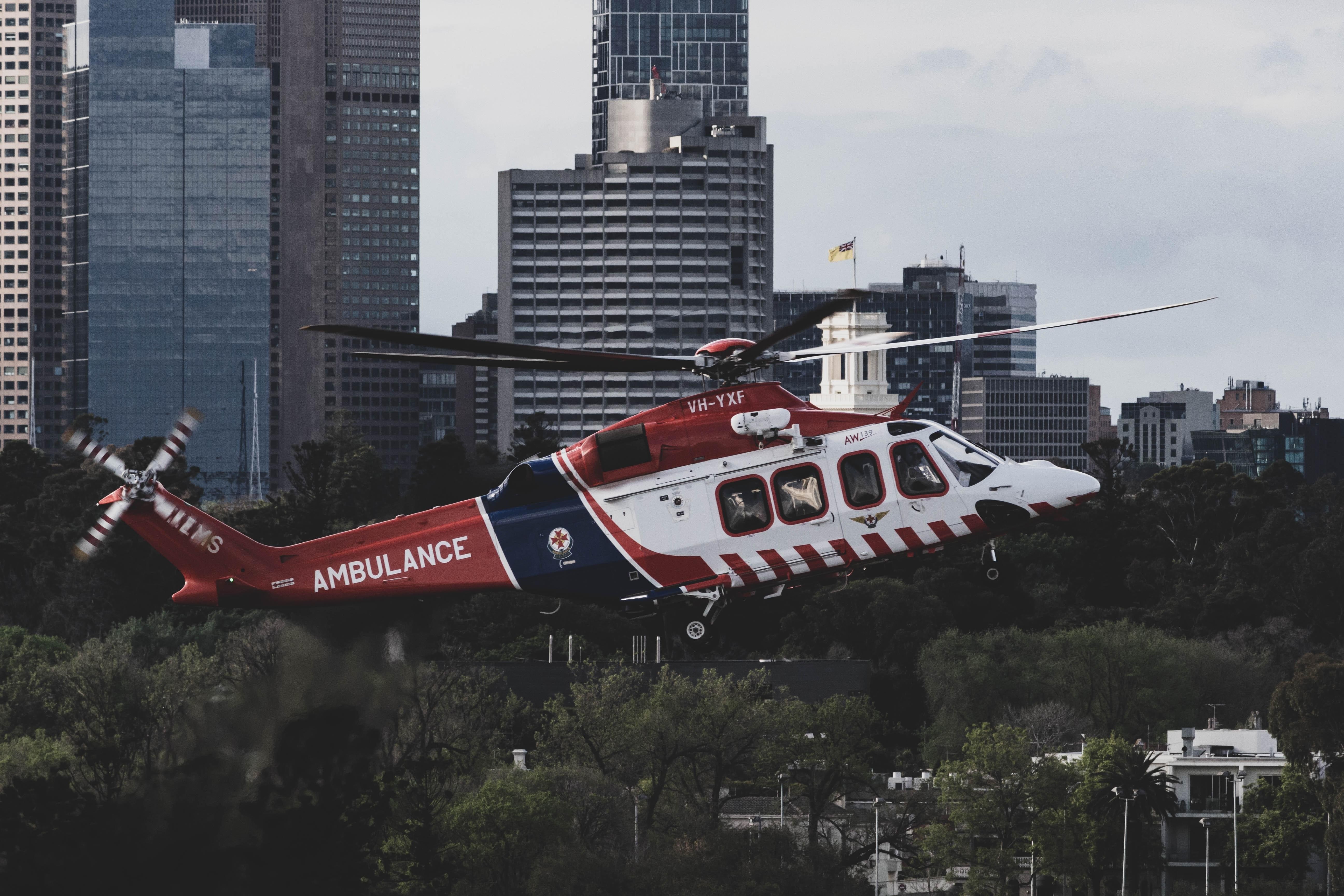 Hubschrauber mit Aufschrift "Ambulance" fliegt vor Hochhäusern