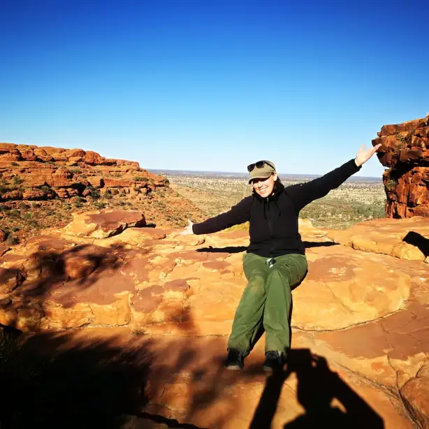 Nicole sitzt auf einem Felsen im Red Centre in Australien.