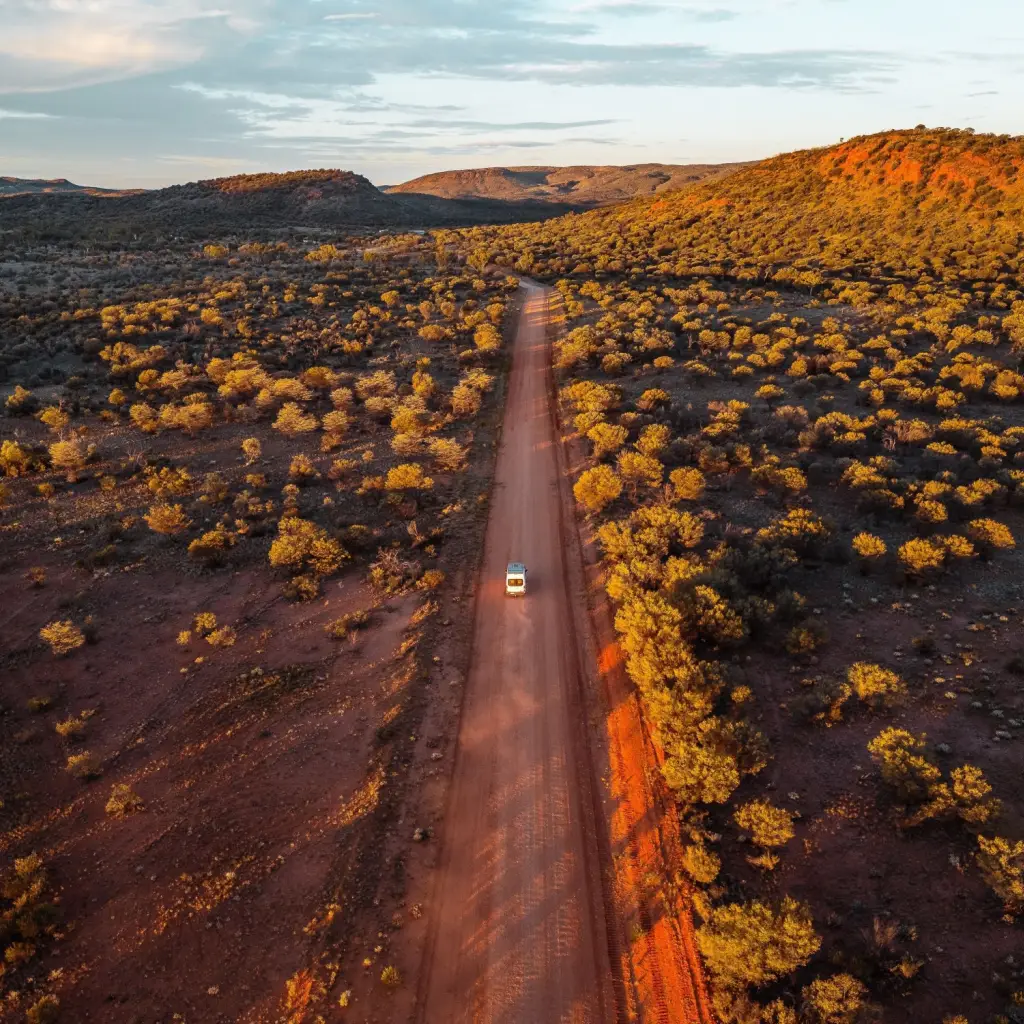 Ein Auto fährt auf einer geraden Straße im Red Centre in Australien.