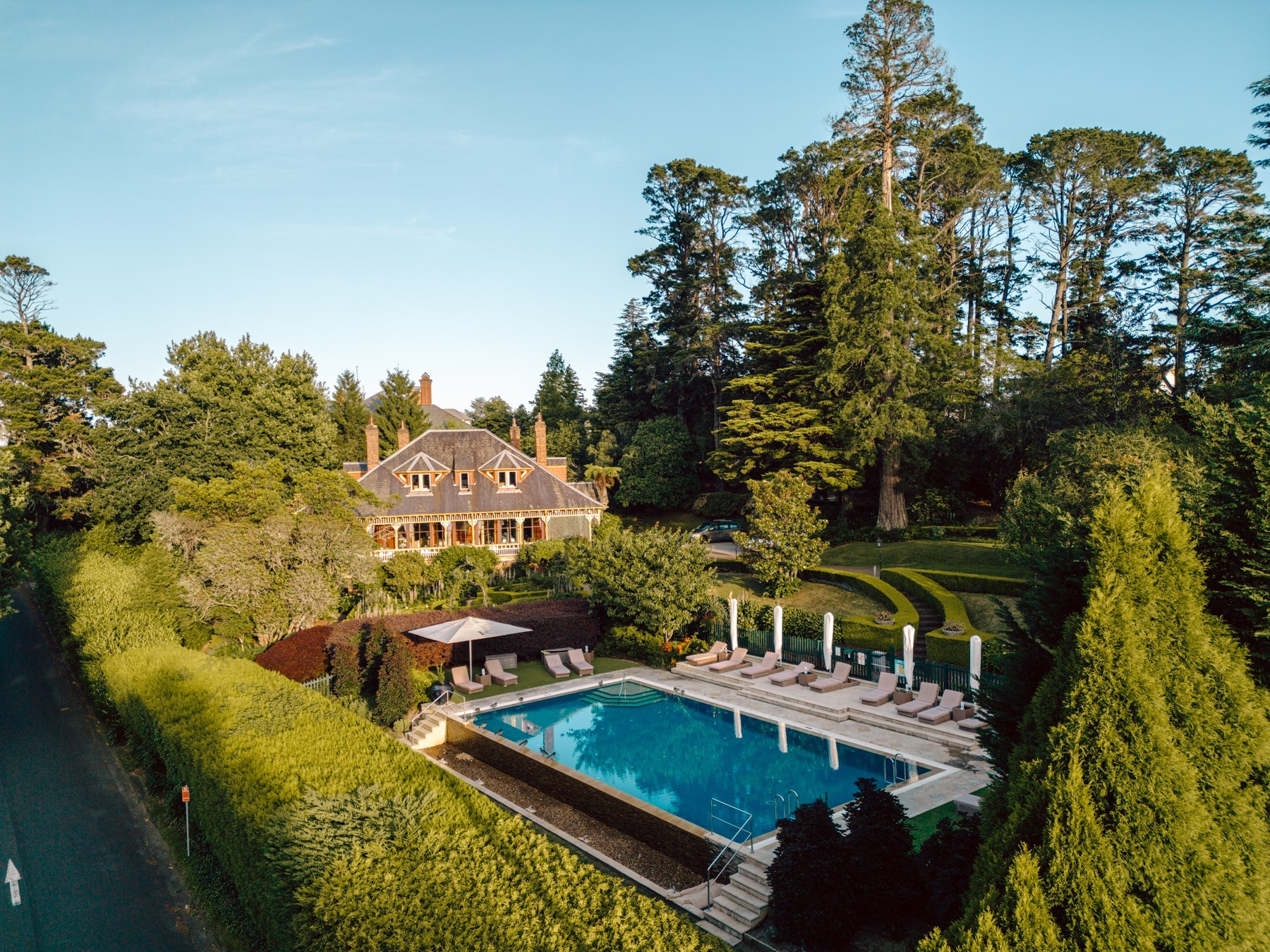 ein Boutique-Hotel und ein Swimmingpool mit Liegestühlen, umgeben von viel Grün