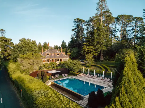 ein Boutique-Hotel und ein Swimmingpool mit Liegestühlen, umgeben von viel Grün