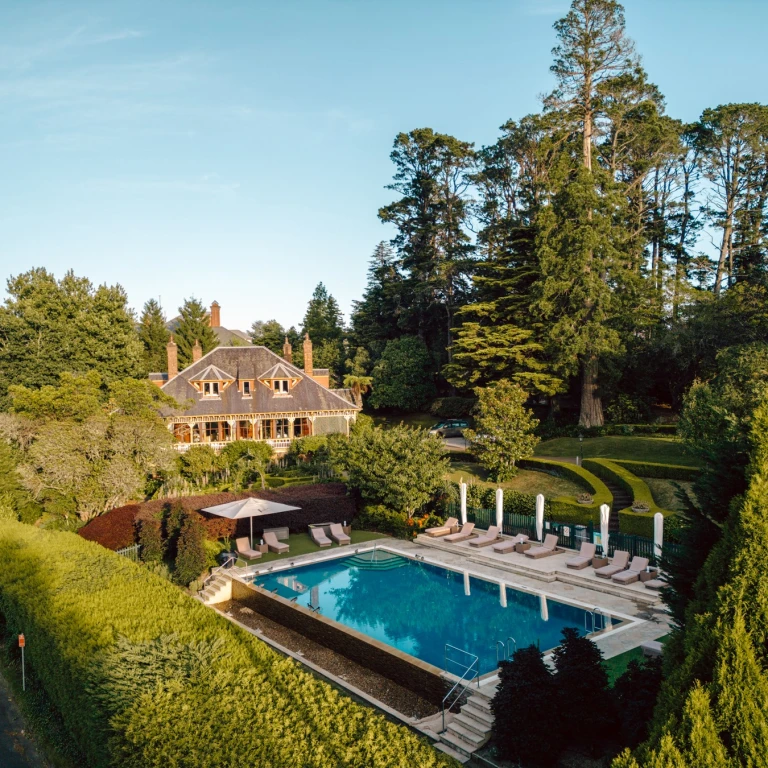 ein Boutique-Hotel und ein Swimmingpool mit Liegestühlen, umgeben von viel Grün