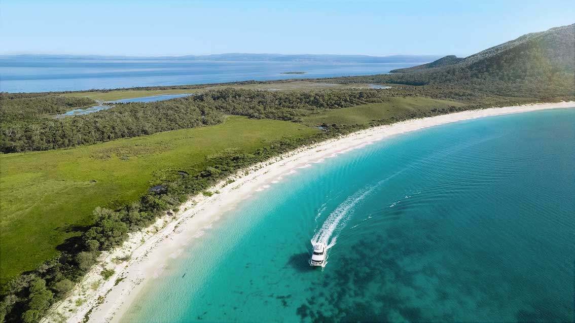 A boat moving across the coast of Wineglass bay in Australia