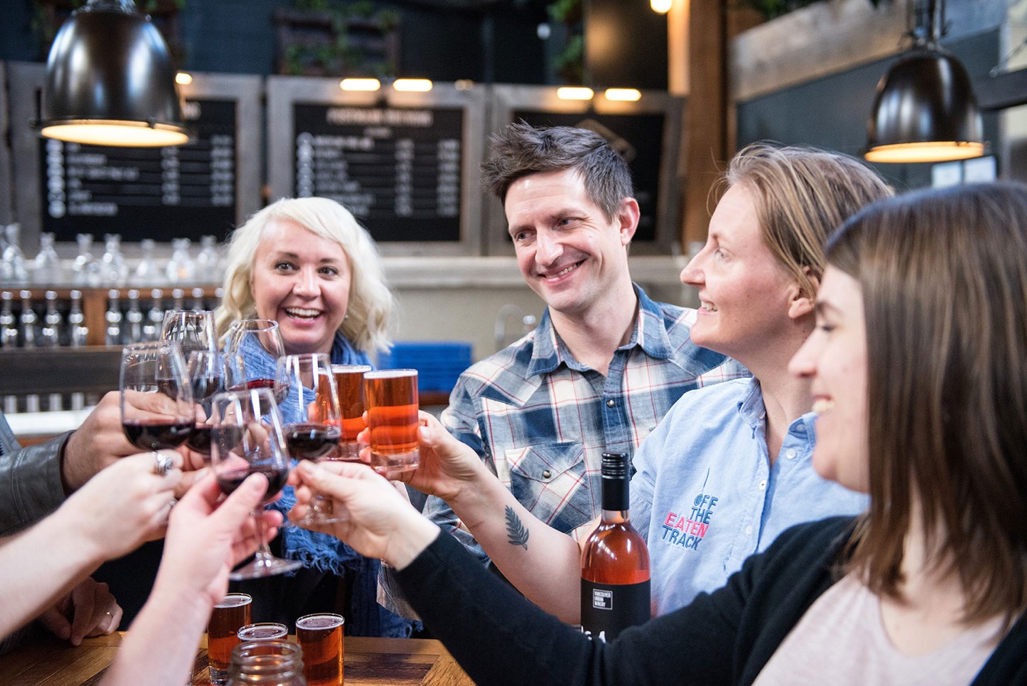 A group of people raise their glasses of wine and beer during a food tour in Victoria, British Columbia, Canada