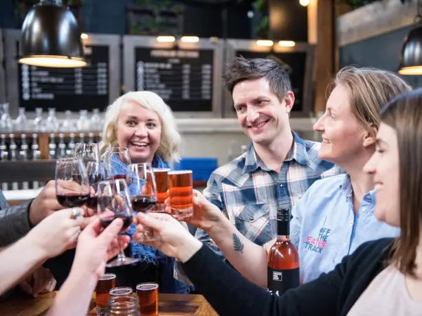 A group of people raise their glasses of wine and beer during a food tour in Victoria, British Columbia, Canada