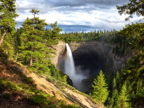 Großer Wasserfall umgeben von Klippen und Bäumen in Wells Gray