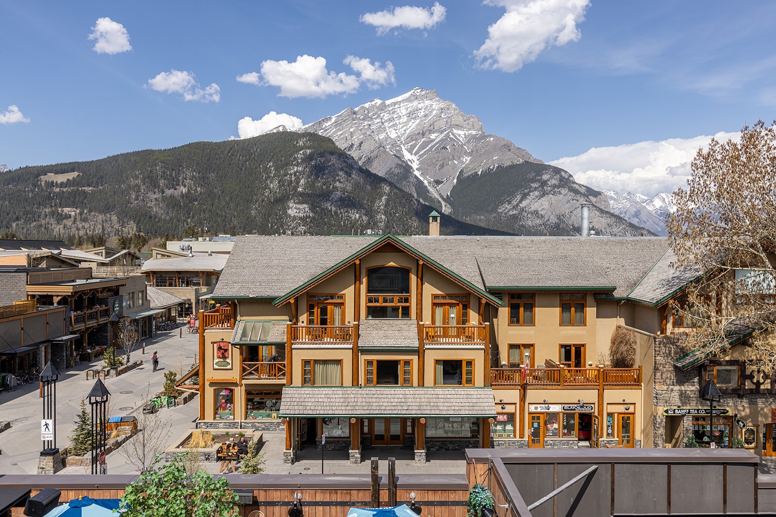 Berglodge im Herzen der Innenstadt von Banff, Kanada, mit Holzbalkonen und einem dramatischen schneebedeckten Rocky-Mountain-Gipfel direkt hinter dem Gebäude