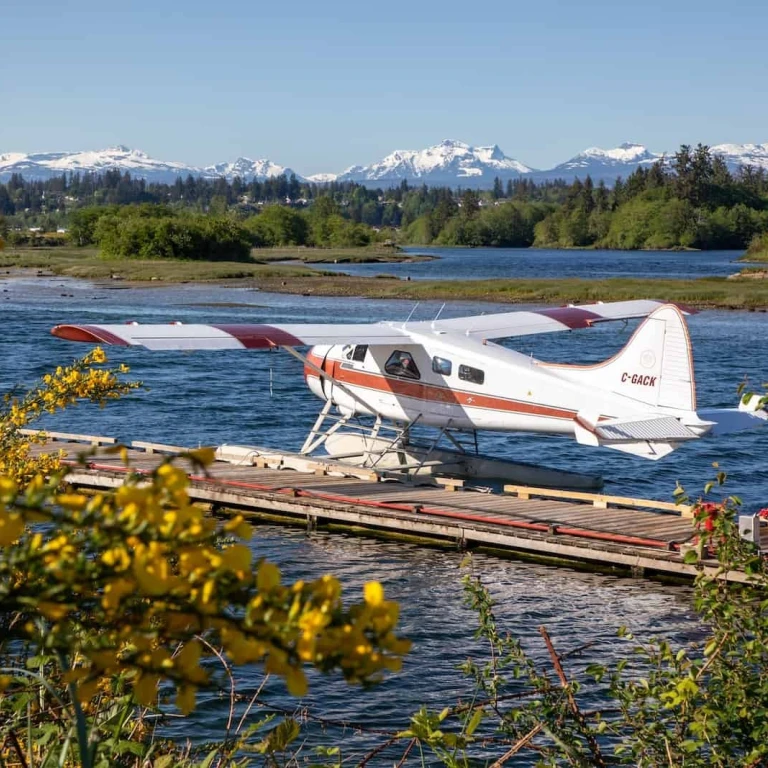 Kleines Wasserflugzeug hält an Steg in Vancouver Island mit Bergen im Hintergrund