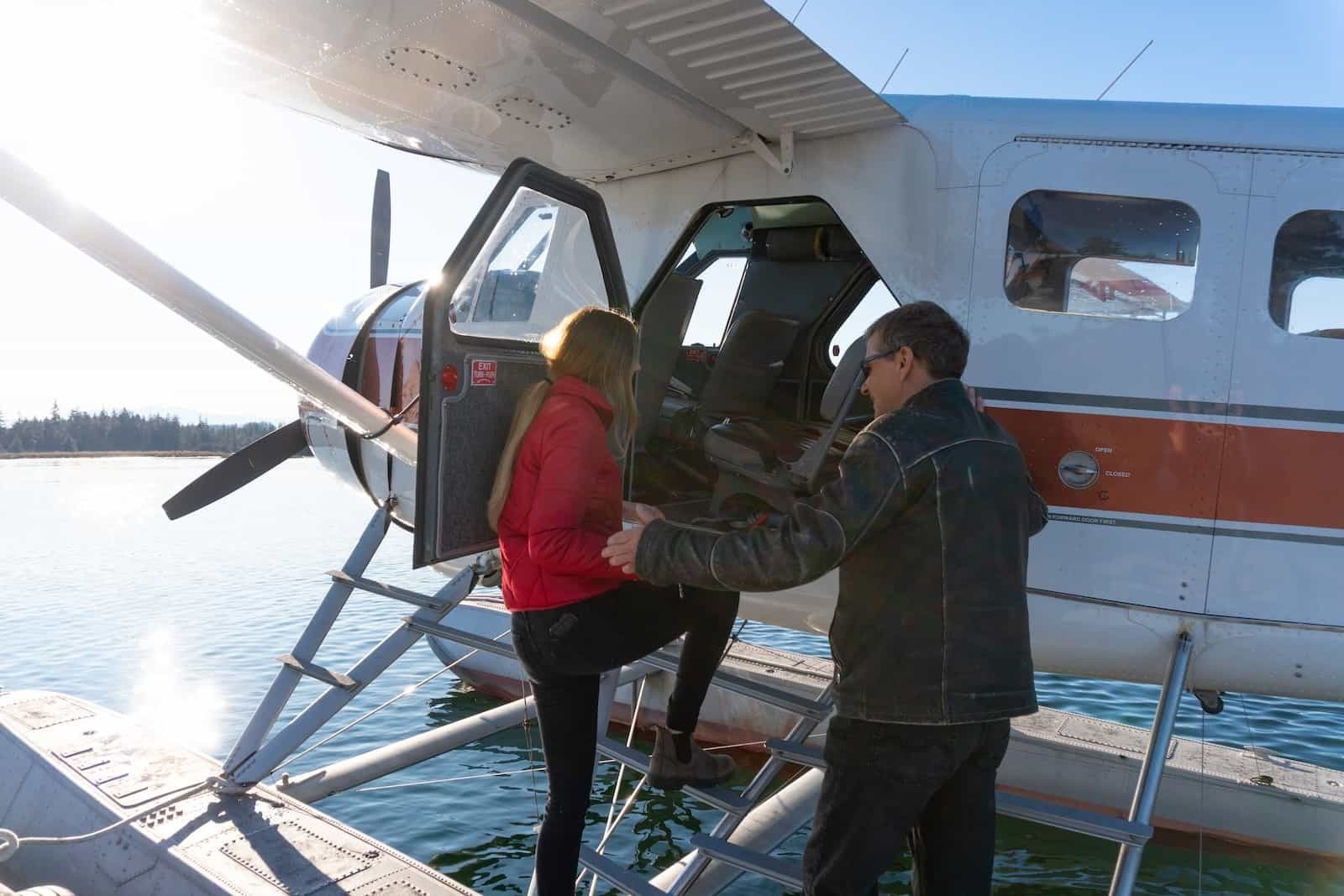 Pilot hilft Frau beim Einsteigen in ein Wasserflugzeug