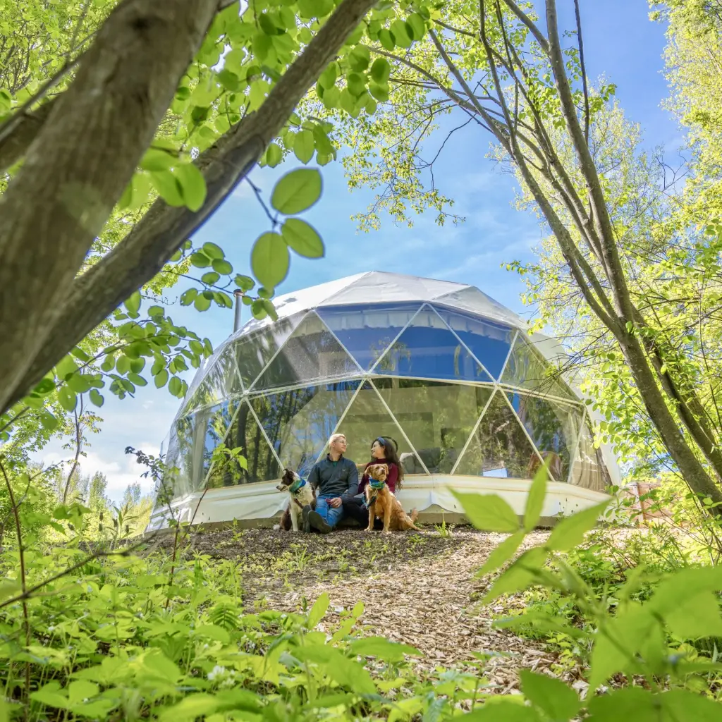 Paar mit Hund sitzt vor Glamping Dom in Kanada
