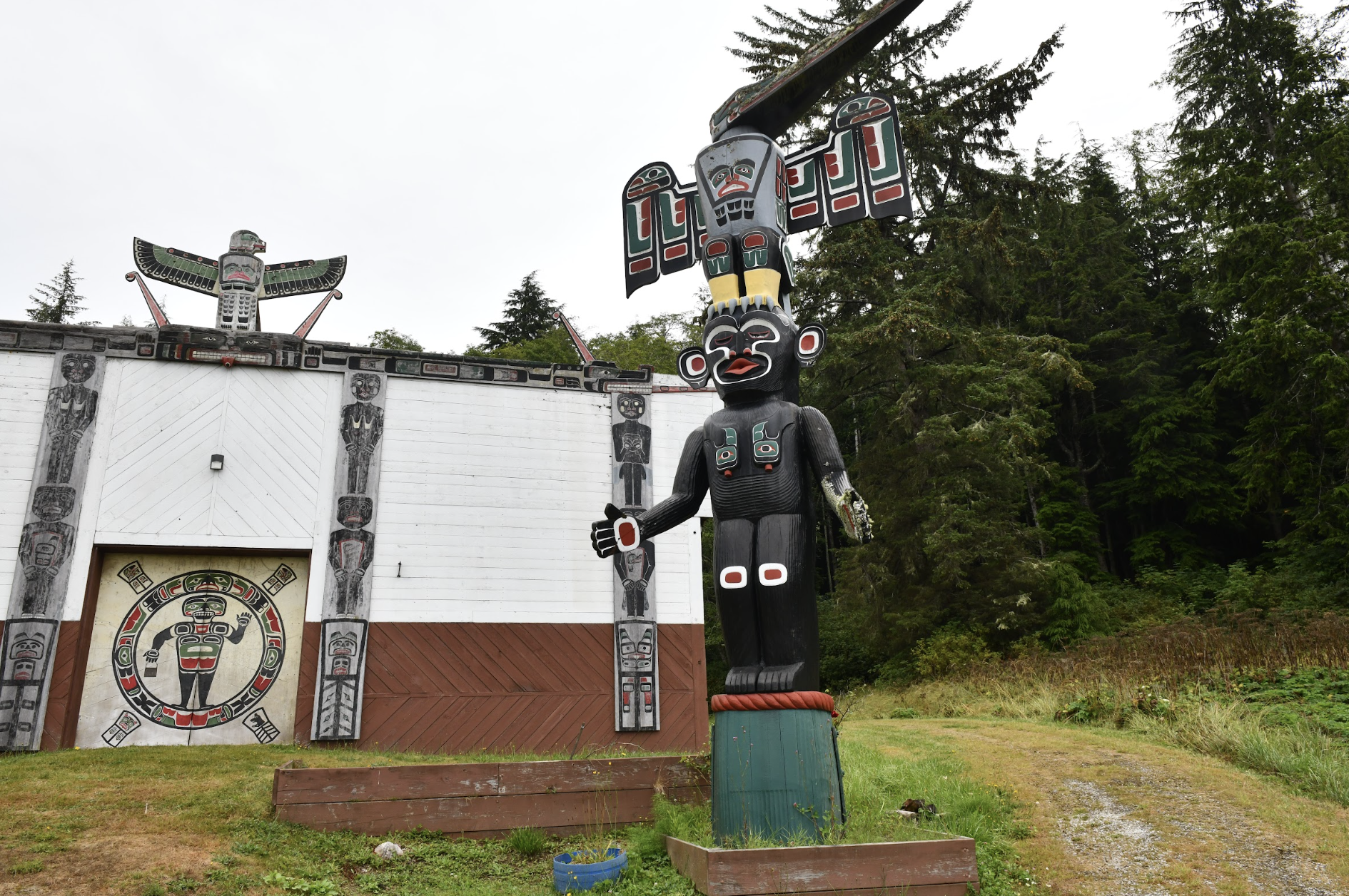 Geschnitzter und bemalter Totempfahl der Ureinwohner und traditionelles Clan-Haus mit Kunstwerken der First Nations an der Pazifikküste von British Columbia, Kanada