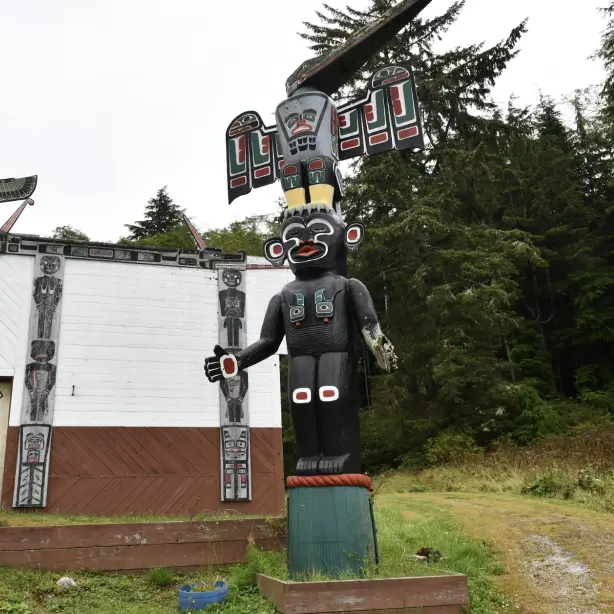 Geschnitzter und bemalter Totempfahl der Ureinwohner und traditionelles Clan-Haus mit Kunstwerken der First Nations an der Pazifikküste von British Columbia, Kanada