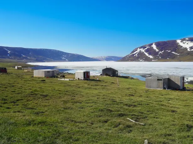 Eine Siedlung der Inuit auf einer weiten Wiese an einem zugefrorenen See