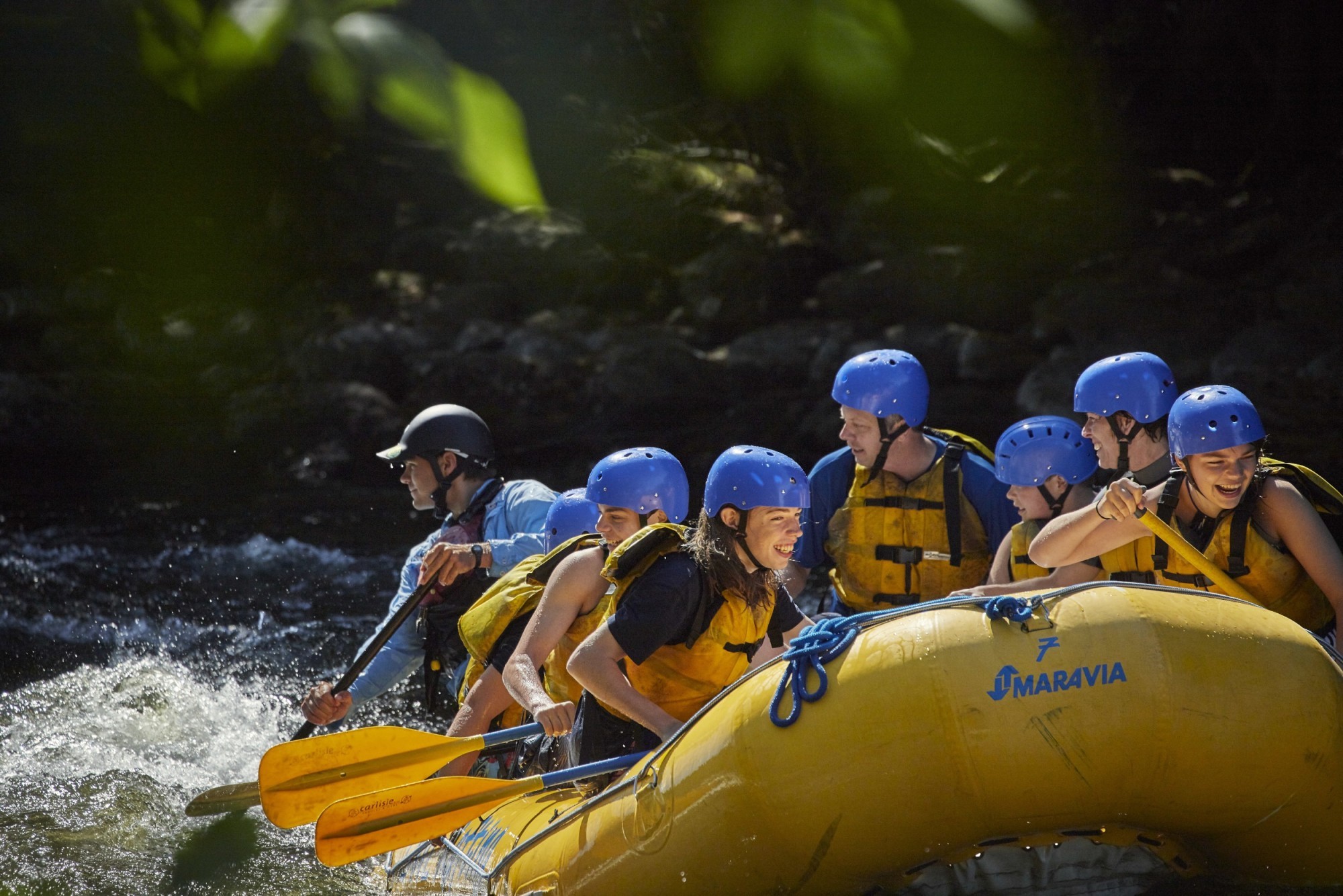 A group smile and laugh as they white water raft down the Madawaska River in Canada