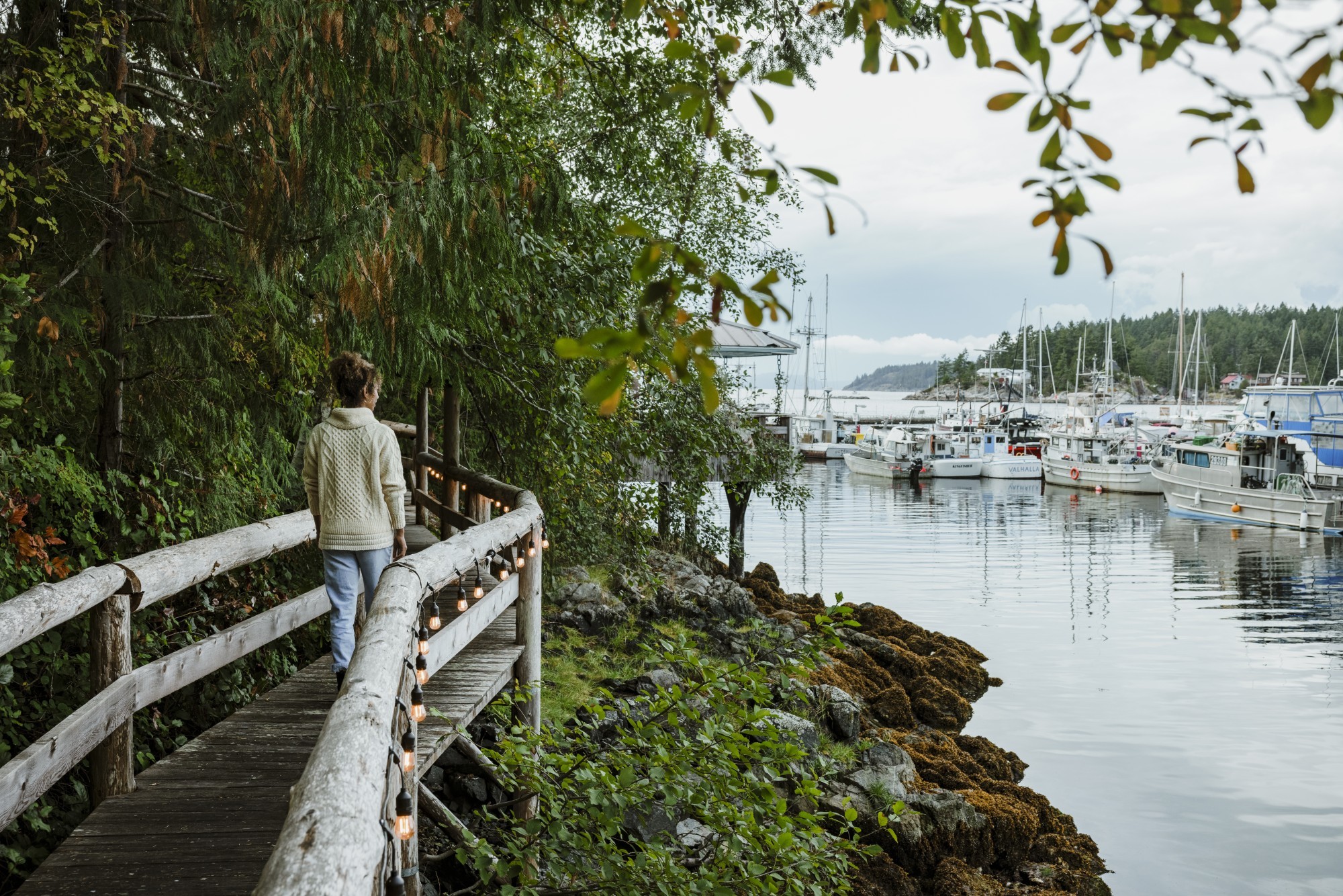A woman walking along a bridged pathway in Sunshine Coast harbour