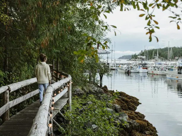 A woman walking along a bridged pathway in Sunshine Coast harbour