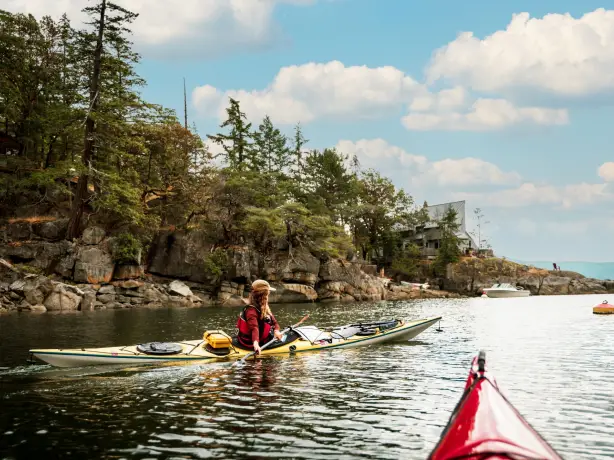 A woman kayaking along the shoreline of sunshine coast