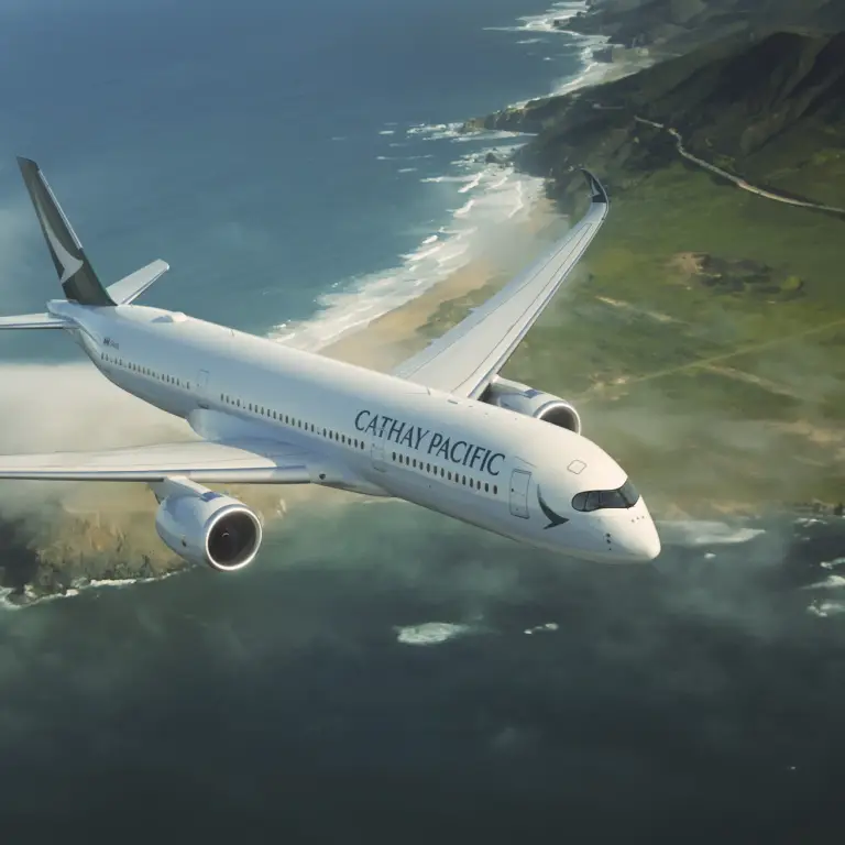 A Cathay Pacific airplane flies over the coastline and sea