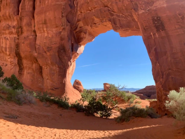 Roter Felsbogen auf rotem Sand in den USA