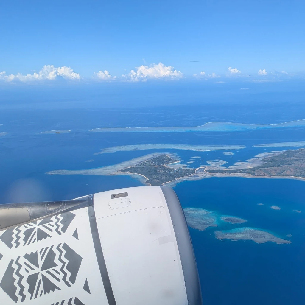 Uitzicht uit het raam van een vliegtuig van Fiji Airways dat over de eilanden van Fiji vliegt