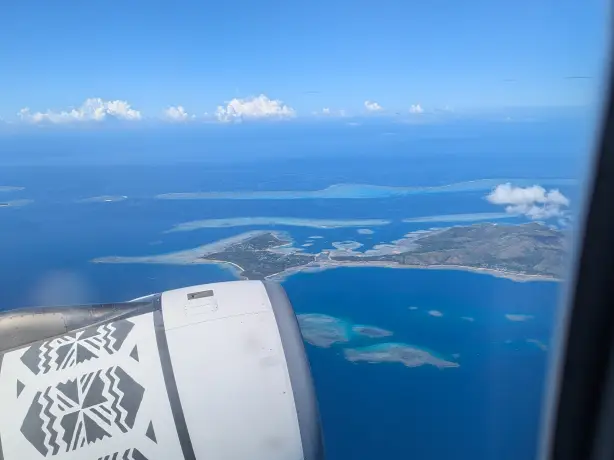 Blick aus dem Fenster eines Flugzeugs der Fiji Airways, das die fidschianischen Inseln überfliegt