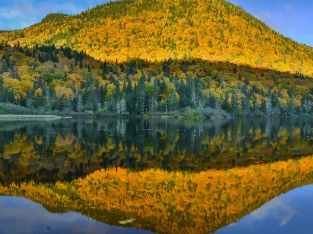 Herbstlich gefärbter Berg spiegelt sich in einem ruhigen See im Jacques Cartier National Park