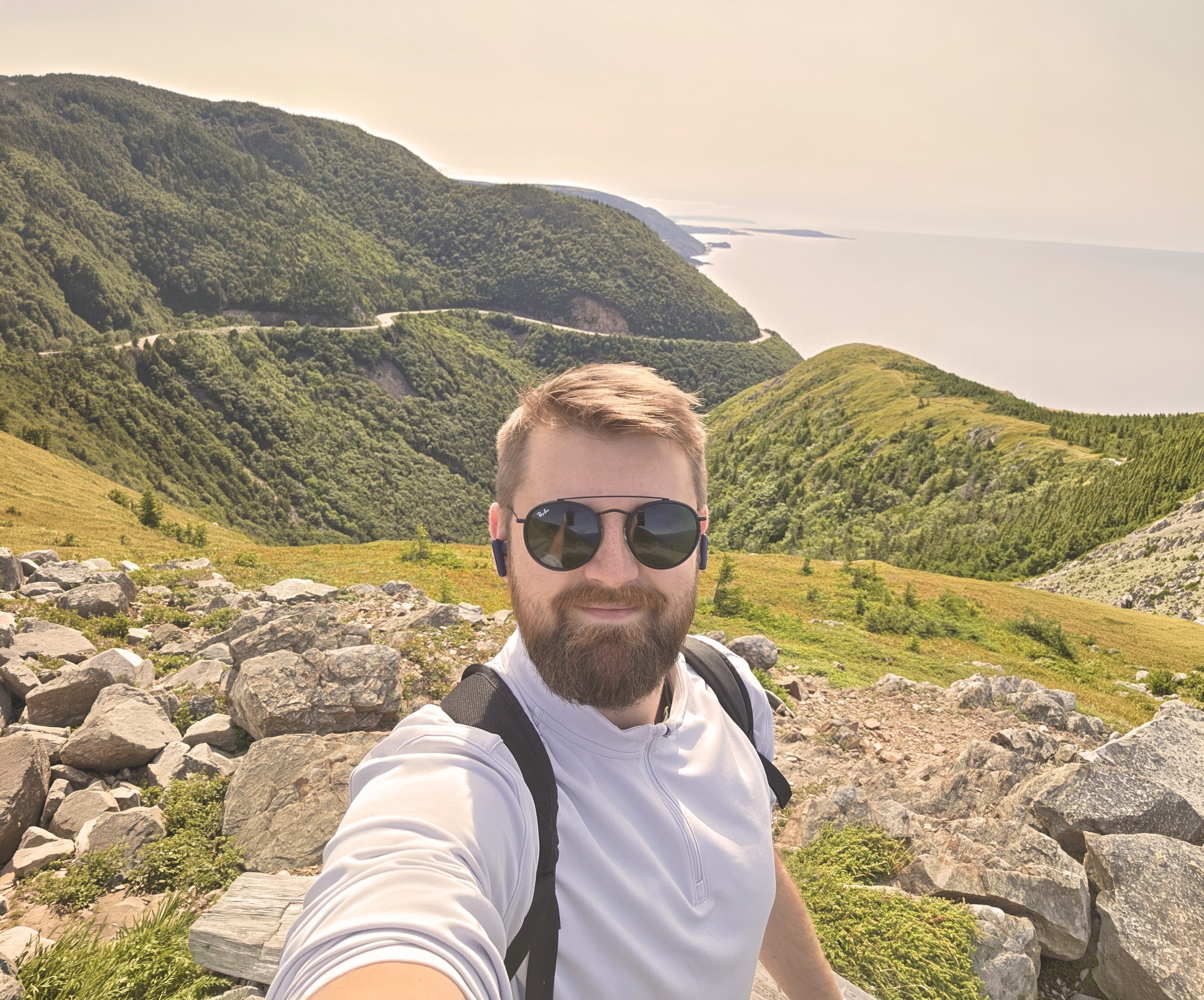 Luke, Travelessence Expert, taking a selfie with mountains and coast in the background