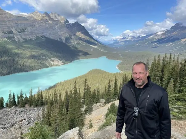 Mann steht vor Bergen und See in Kanada
