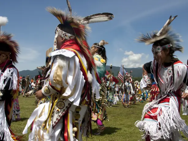 Een dansende groep First Nations, dragen traditionele kleding en hoofddeksels